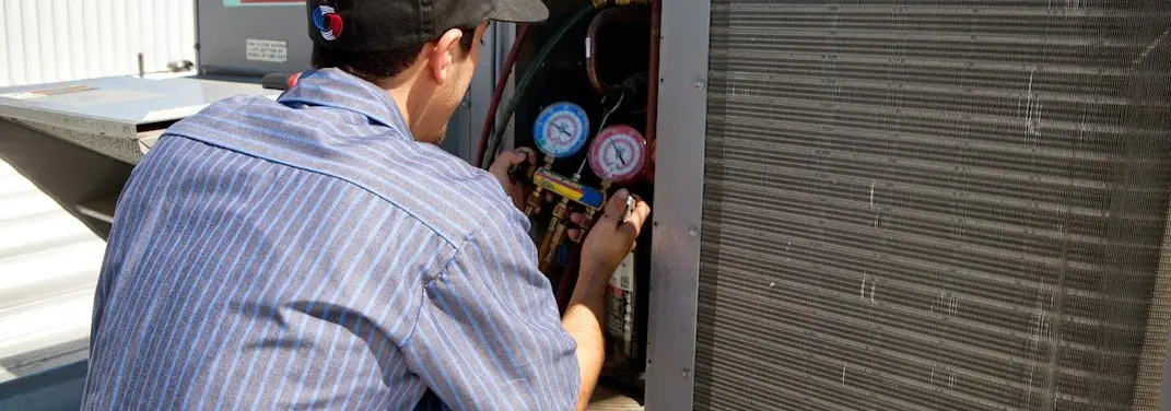 HVAC technician servicing a condenser unit in Roseburg